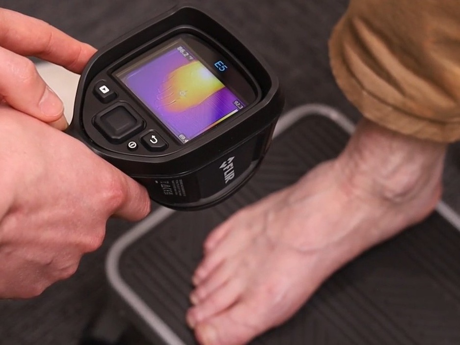 A thermal imaging camera held over a bare foot